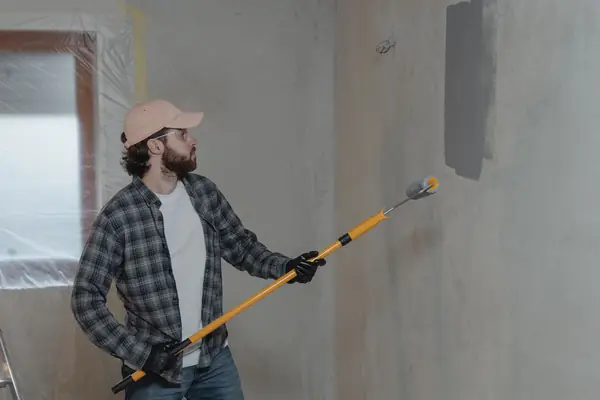 Painter rolling grey paint onto an interior wall in Madison